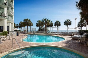 Relax by the oceanfront pool surrounded by lounge chairs and umbrellas.