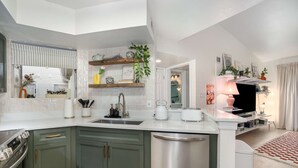A modern kitchen with a central island, stainless steel appliances, and green cabinets.