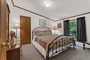 Une chambre à coucher avec un lit, une porte en bois, une fenêtre avec des rideaux et une lampe.
