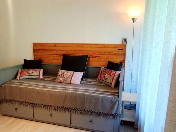 A bed with a wooden headboard, three pillows, and a blanket.
