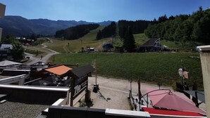 A mountain view with a clear sky, a road leading through a valley, and a building with a sign that reads 'KIMIUM'. - Cozy studio at the foot of the slopes with balcony, TV and ski locker (Les Adrets-Prapoutel)