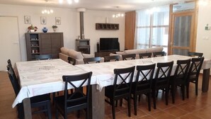 A dining area with a long table and chairs, a sofa, a television, and a cabinet with decorative items. - Family eco-cottage with garden, near hiking trail (Mesples)