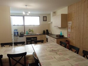 A compact kitchen with a dining table, chairs, and a window.