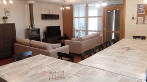 A dining area with a long table, several chairs, a sofa, a television, and a cabinet. - Family eco-cottage with garden, near hiking trail (Mesples)