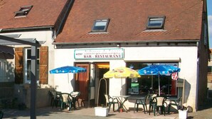 A bar and restaurant with outdoor seating, a tiled roof, and a signboard. - Family eco-cottage with garden, near hiking trail (Mesples)