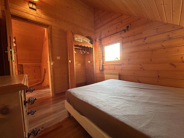 A wooden cabin room with a bed, a small table, and a window. - Charming Chalet for 8 with Pool, Terrace, and Mountain Views near Fontettes Lift (La Joue du Loup)