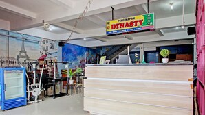 A hotel reception area with a large sign for 'PENGINAPAN DYNASTY' and a staircase leading to upper floors. - Capital O 93361 Dynasty Inn Syariah (Pekalongan)