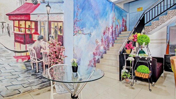 A café with outdoor seating, a staircase with floral decorations, and a glass table with potted plants. - Capital O 93361 Dynasty Inn Syariah (Pekalongan)