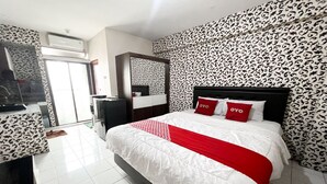 Une chambre d’hôtel avec un grand lit, une armoire, un miroir et un papier peint à motifs.