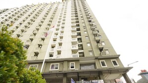 Un immeuble de grande hauteur doté de nombreux balcons et surmonté d’un drapeau.