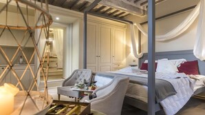 Un dormitorio con cama, una silla, una mesa con una vela y un armario.