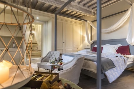 A bedroom with a bed, a chair, a table with a candle, and a wardrobe.
