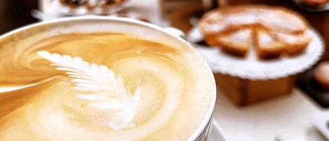 Una tazza di caffè con decorazione a disegno nel latte su un piattino.