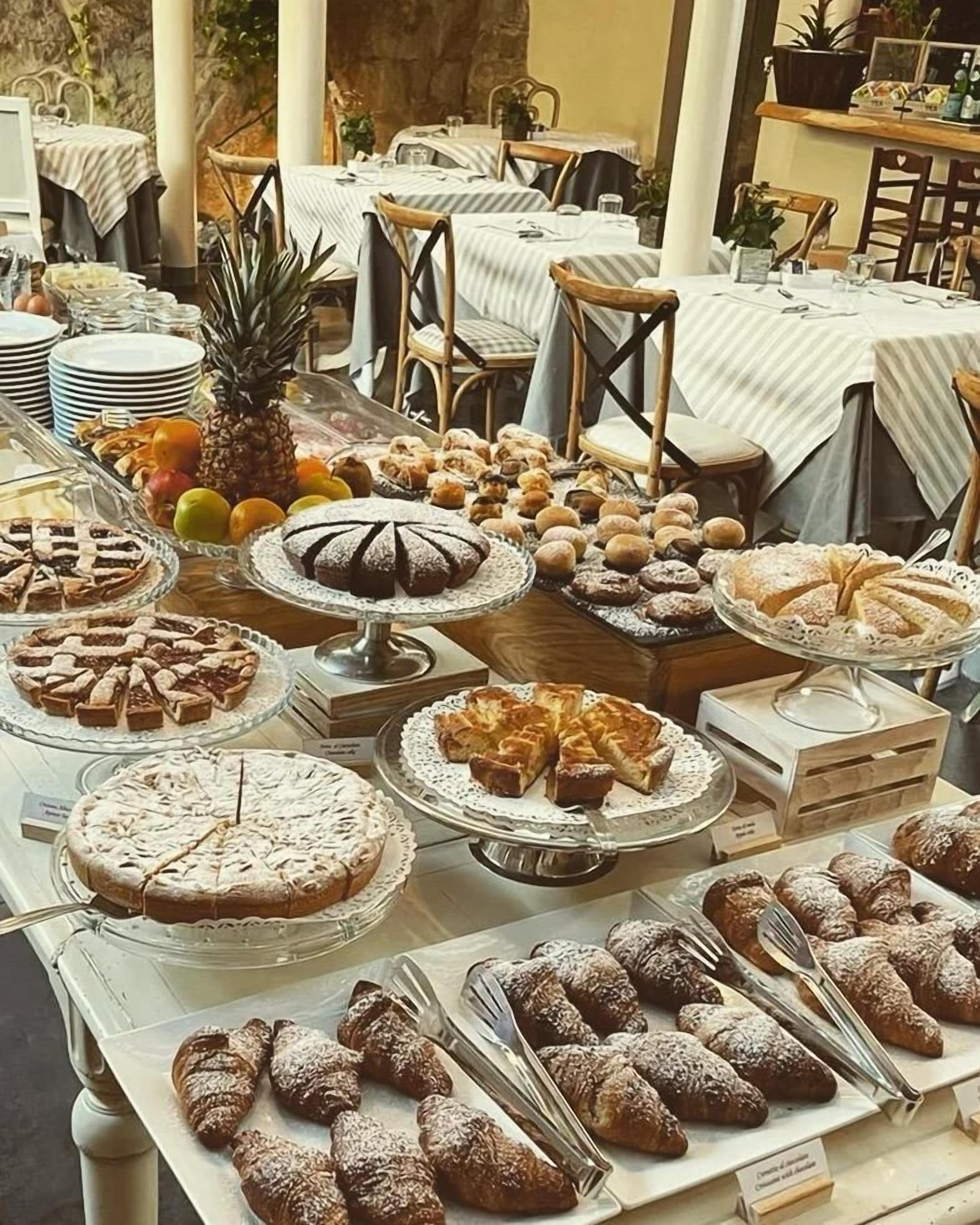 A buffet with various desserts and fruits, including pies, cakes, and pastries, arranged on tables with white tablecloths.