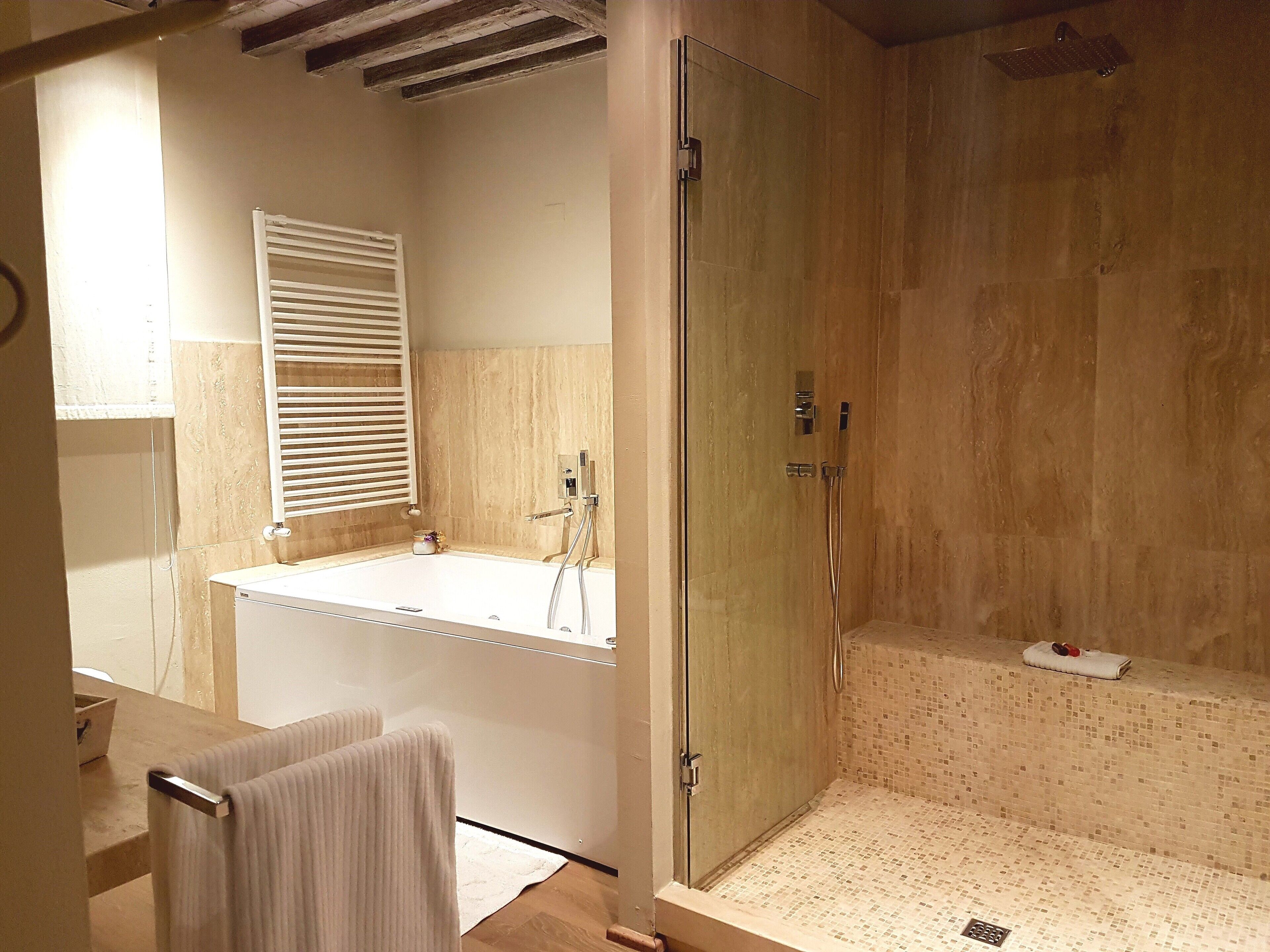 Un baño moderno con ducha de vidrio, un espejo grande y un tocador de madera.