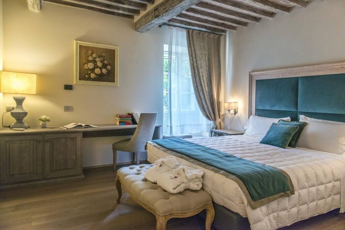 A bedroom with a bed, a desk, a chair, and a window with curtains.