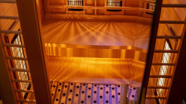 Interior de ascensor con paneles de madera, un panel de control y un sistema de ventilación.