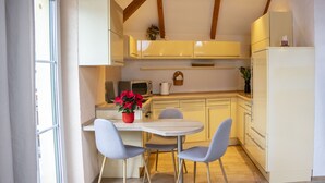 Una cocina con una mesa de comedor, sillas, un refrigerador y un microondas.
