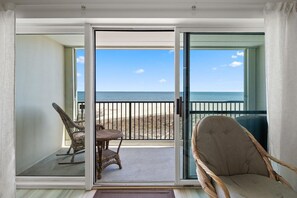 A room with a sliding glass door leading to a balcony with a view of the beach. - One Bedroom Oceanfront Condo with Outdoor Pool (Ocean City)