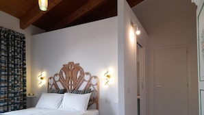 Une chambre à coucher avec une tête de lit en bois, du linge de lit blanc et des lampes fixées au mur.