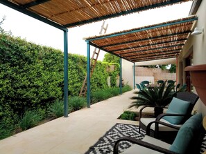 Un patio couvert avec des meubles d’extérieur, une échelle et un sol carrelé.