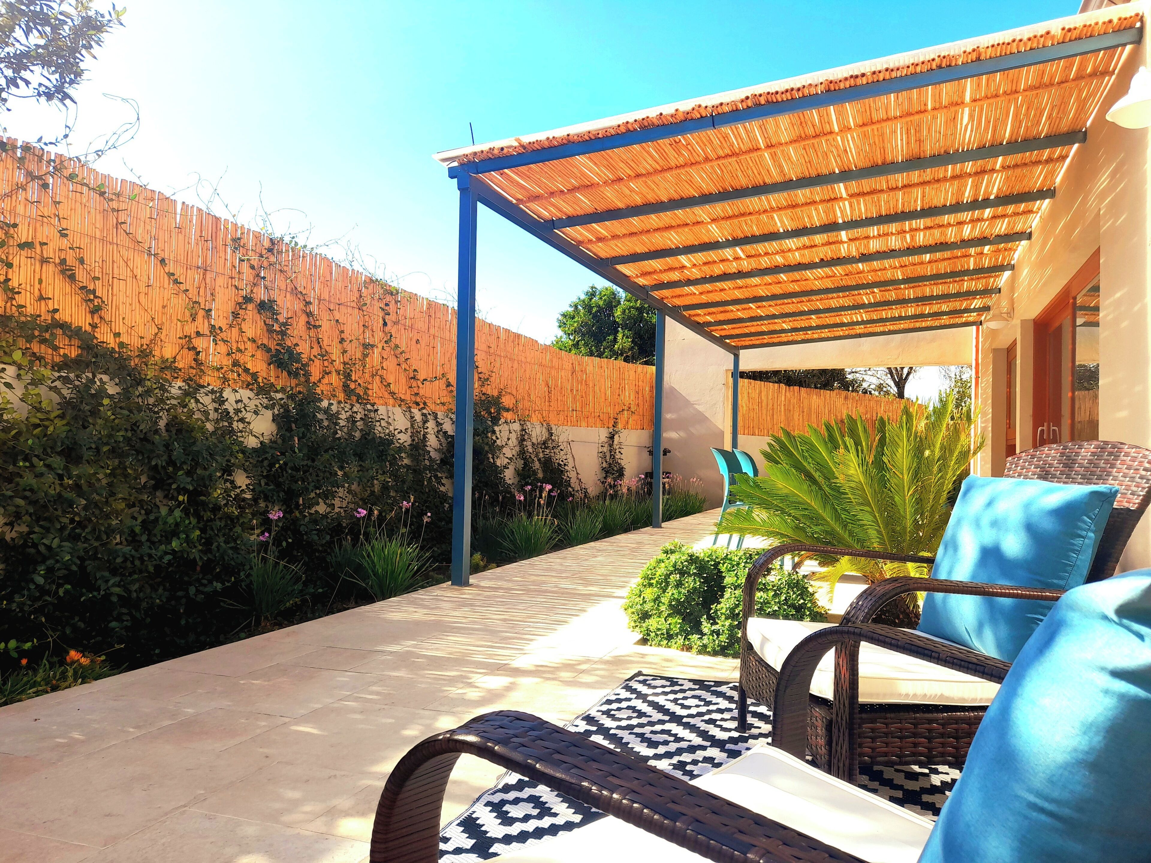 A covered outdoor seating area with wicker furniture and a patterned rug.