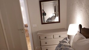 A bedroom with a bed, a dresser, a mirror, and a nightstand with a lamp. - In the heart of a medieval French village. One bed apartment. Pet friendly (Cipières)