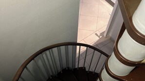Una escalera de caracol con barandilla de madera y balaustres de metal.