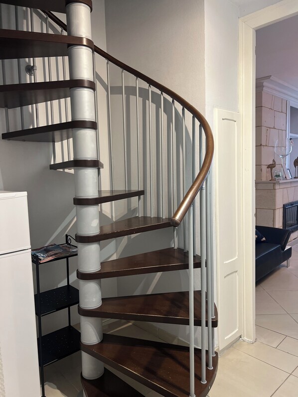 A spiral staircase with a wooden handrail and white balusters, leading to an upper floor. - Le Médoc de Clémence (Lamarque)