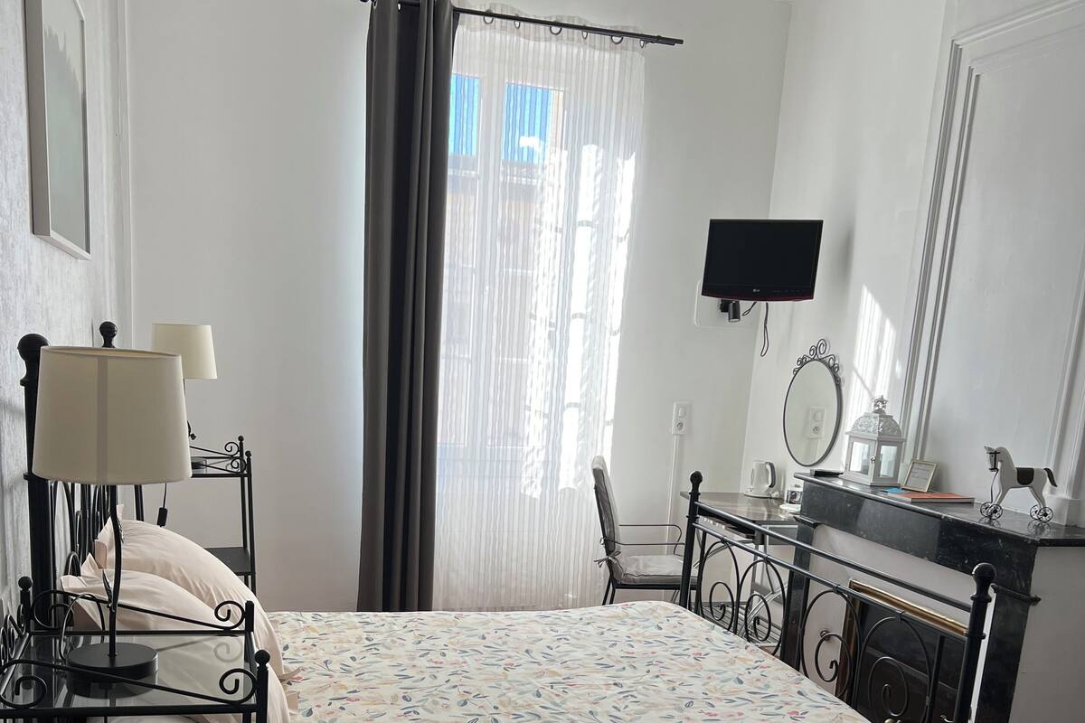 A bedroom with a bed, bedside table, lamp, and a desk with a mirror.