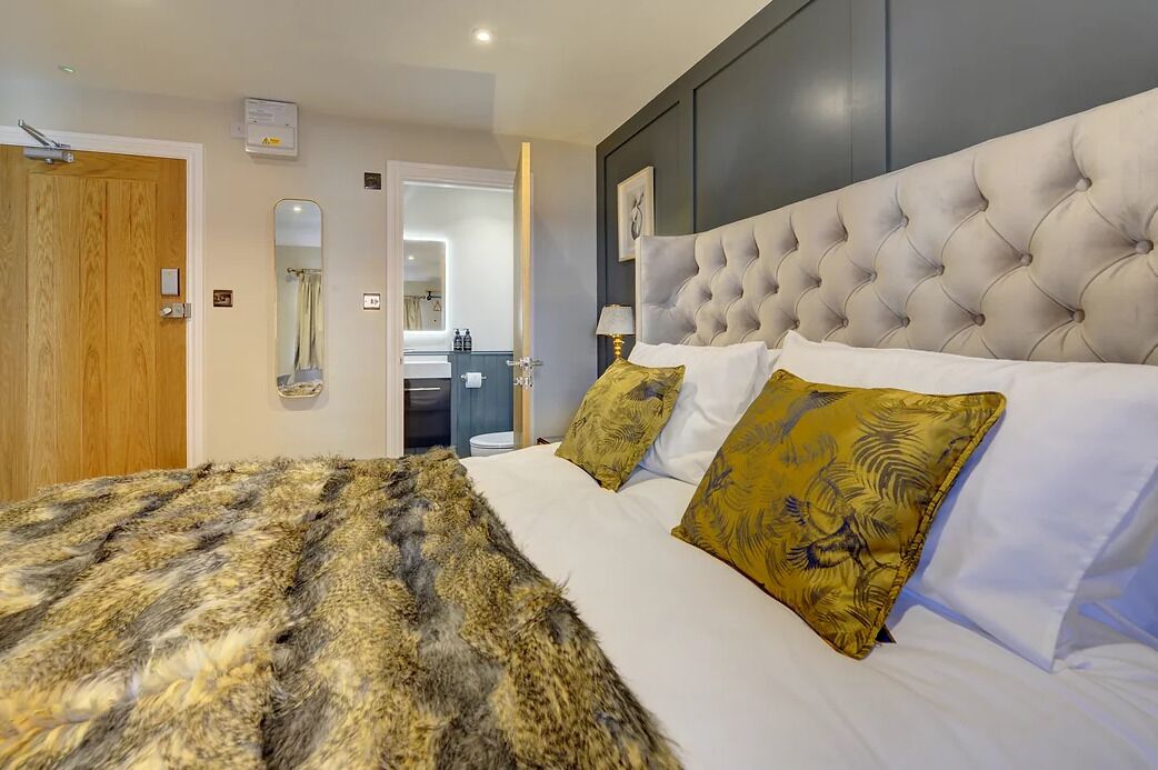 A bedroom with a large bed, a tufted headboard, and a mirror above the bed.