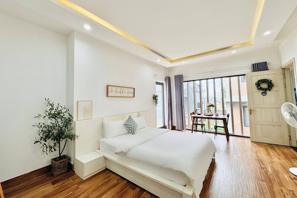 A modern bedroom with a large bed, a small table, and a fan.