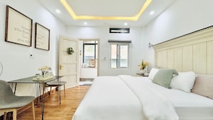 Un dormitorio con cama, mesita de noche, lámpara y escritorio con silla. Hay una ventana con vistas al exterior.