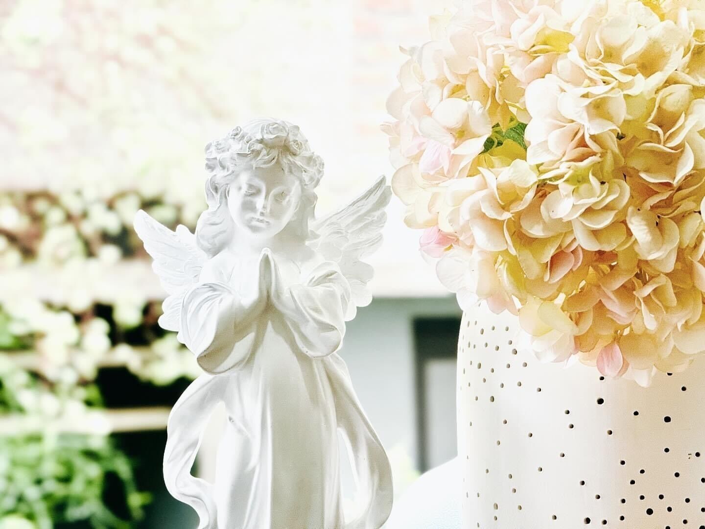 A white angel figurine and a vase with pale yellow flowers.
