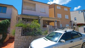 A two-story building with a car parked in front. - Holiday apartment with air conditioning (Pula)