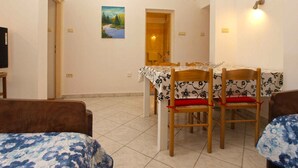 A dining area with a table set for four, surrounded by wooden chairs with red cushions. - Holiday apartment with air conditioning (Pula)
