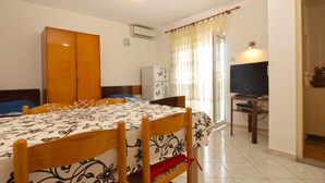 A bedroom with a bed, a desk, a television, and a wardrobe. - Holiday apartment with air conditioning (Pula)