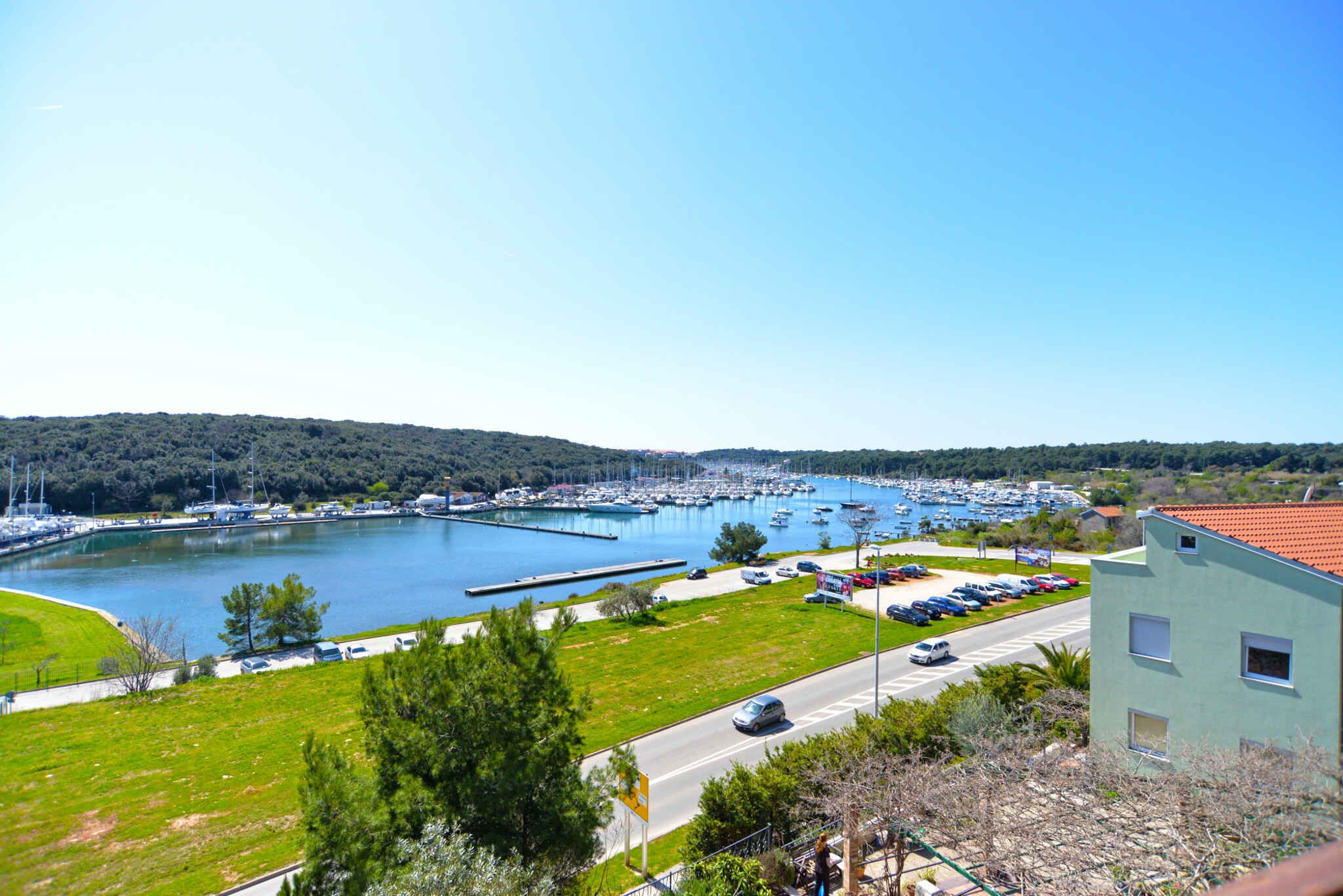 A marina with boats, a parking lot, and a building with a red roof.