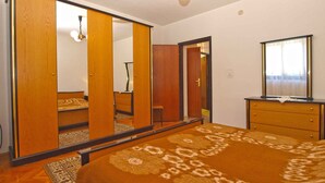 Une chambre à coucher avec un grand miroir, une armoire en bois et un lit recouvert d’une couvre-lit à motifs.