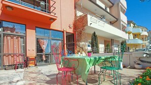 An outdoor patio with a table and chairs, a building with balconies, and a clear sky. - Holiday apartment with air conditioning (Pula)