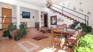 A spacious living area with a dining table, chairs, a staircase, and various plants. - Holiday apartment with air conditioning (Pula)