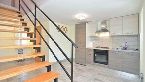 Une cuisine moderne avec un plancher en bois, une cuisinière encastrée et une hotte en acier inoxydable.
