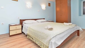 Une chambre à coucher comprenant un lit, des tables de chevet, une armoire et des lampes fixées au mur.