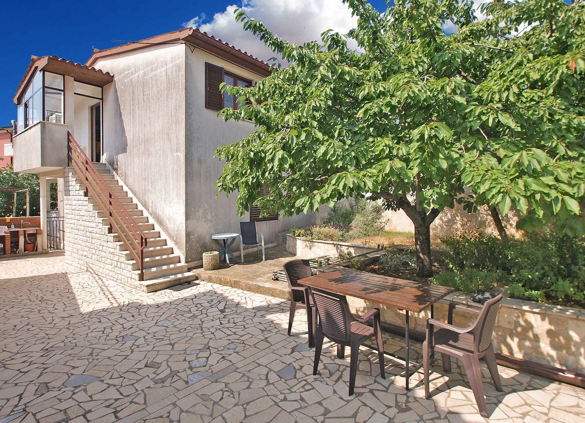 Uma casa com um pátio de pedra, uma escadaria e uma área de jantar com mobiliário para área externa.