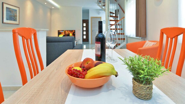 A dining table with a fruit bowl, a bottle of wine, and a potted plant. - Holiday apartment with air conditioning (Pula)