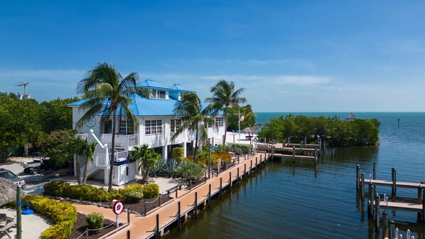A waterfront property with a dock, a pool, and a building with a blue roof.