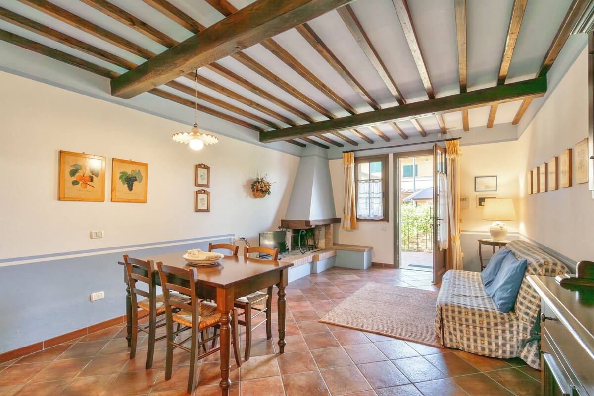 A dining area with a wooden table and chairs, a kitchen with a stove, and a cozy seating area with a sofa.