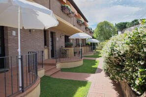 A courtyard with outdoor seating under umbrellas, brick walls, and a well-maintained lawn. - Holiday-Home with pool in San Gimignano (San Gimignano)