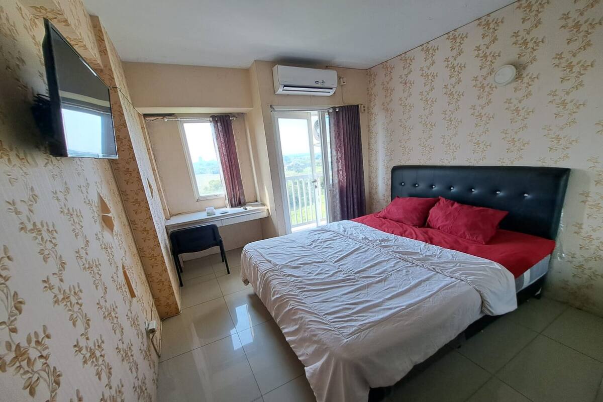 Un dormitorio con cama, escritorio, silla y televisor.