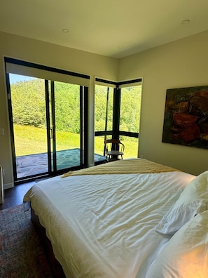 A bedroom with a large bed, a chair, and a painting on the wall. - 4TreesVA: Old Rag Mountain Retreat (Etlan)